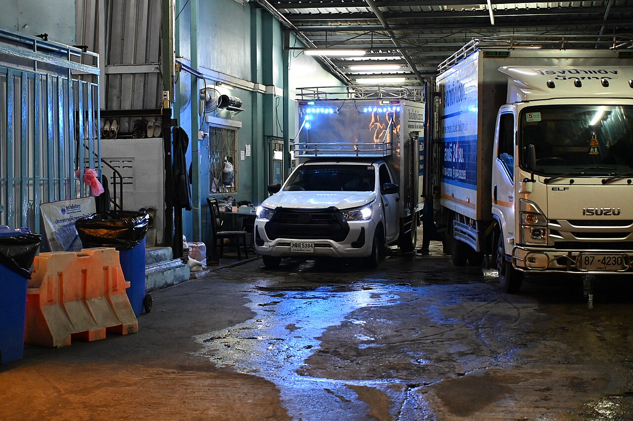 夜間の荷役場に並ぶ配送トラックと作業車両