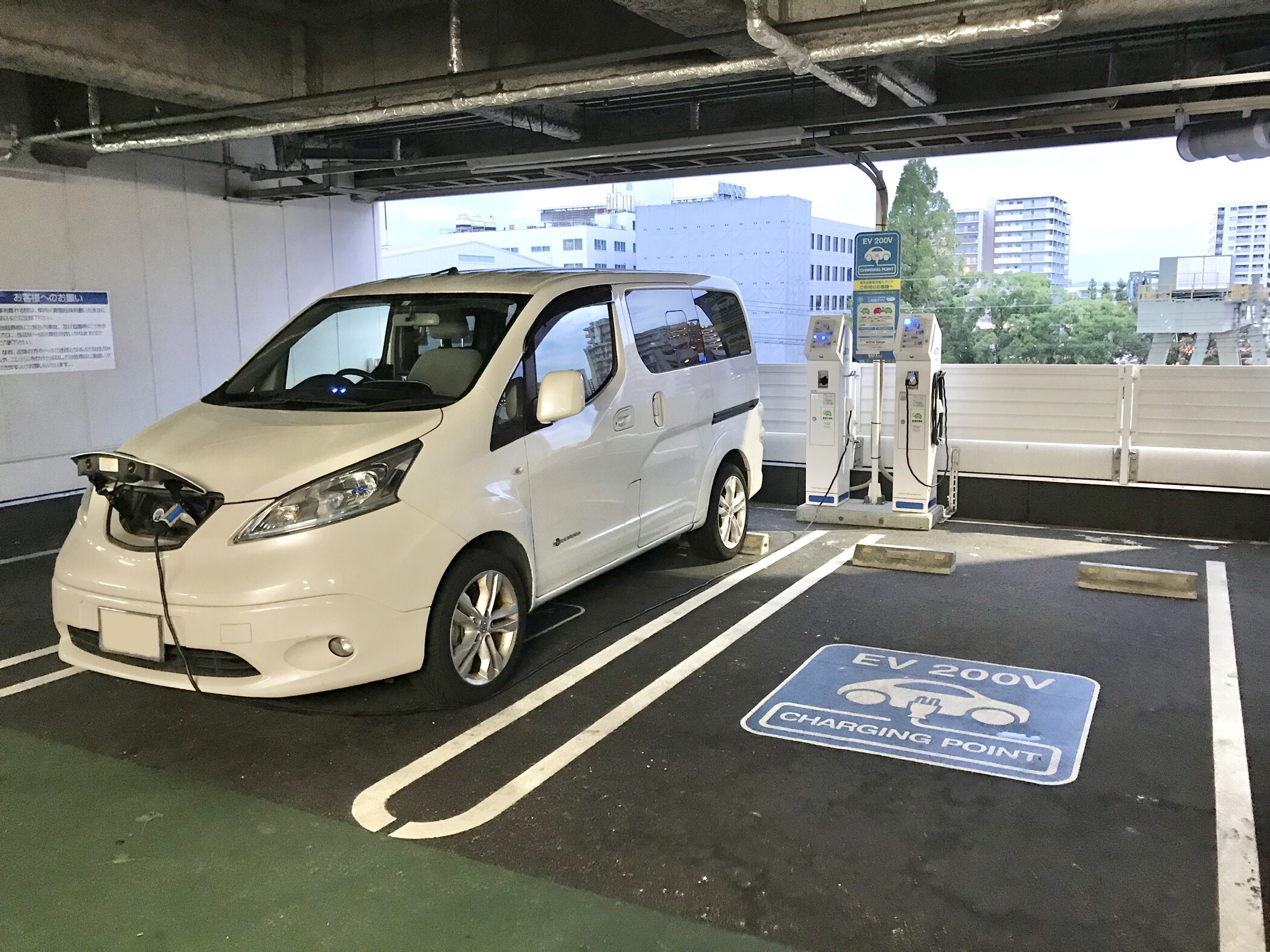 車の近くに設置された日本の普通充電スタンドと接続ケーブルの参考写真