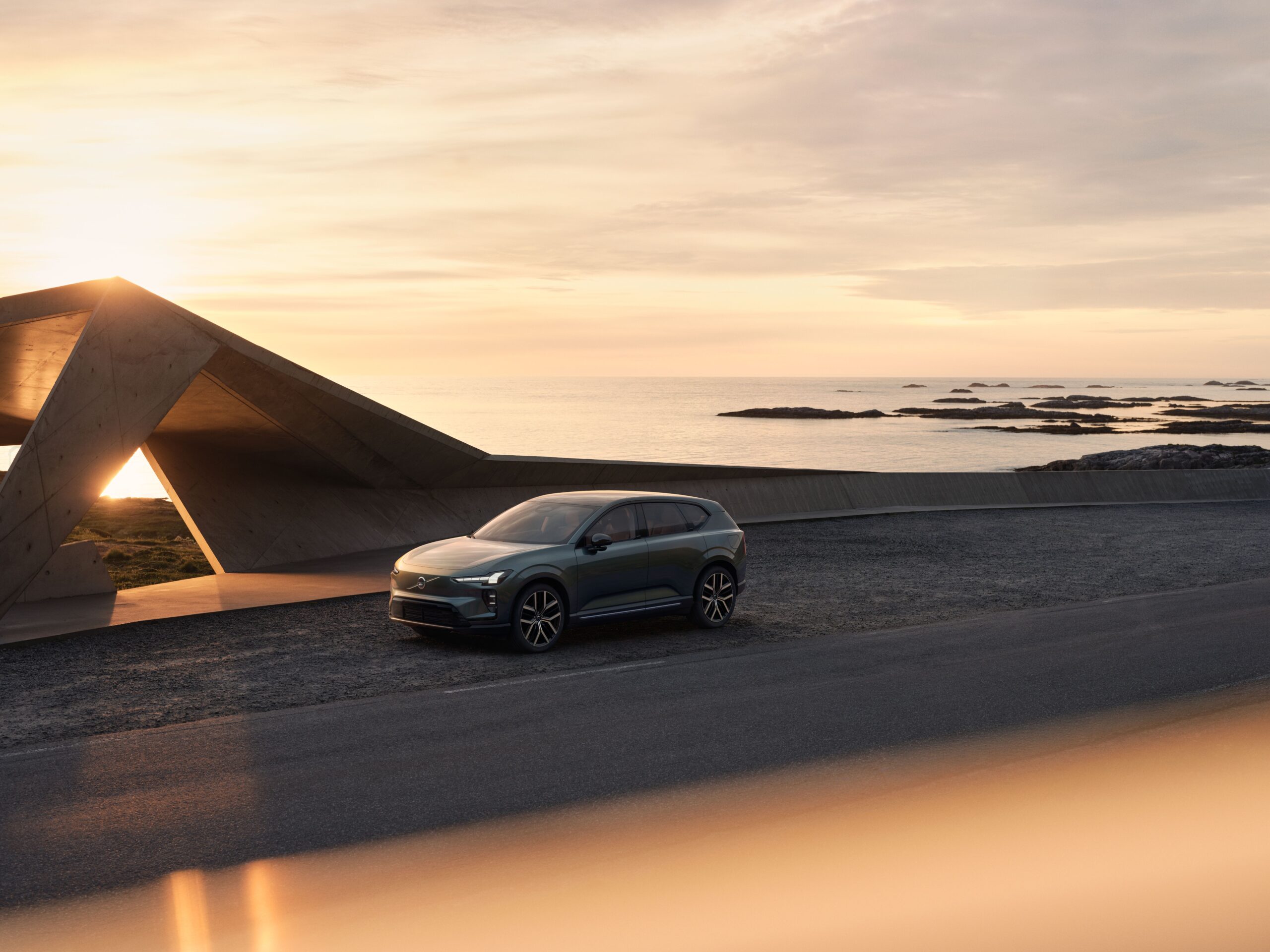 海沿いのコンクリート建築の前に停まるボルボEX60の外観、Volvo Cars公式画像